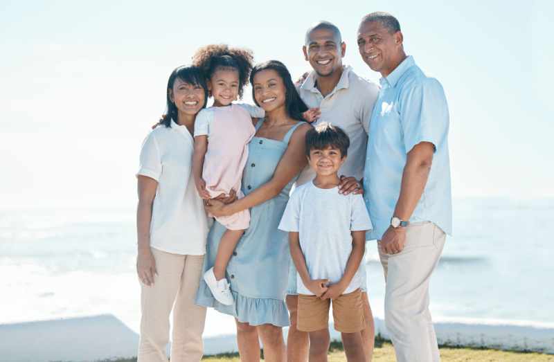 Big family, portrait and smile by ocean